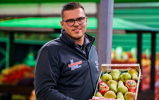 Mitarbeiter der Firma Lührs Fruchtgroßhandel mit einer Kiste Birnen